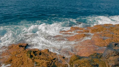 Turquoise waves of the ocean beat against the yellow stones of the shore Stock Footage 120139784