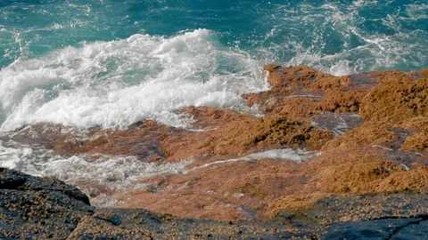 Turquoise waves of the ocean beat against the yellow stones of the shore Stock Footage 120235448