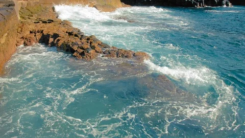 Turquoise waves of the ocean beat against the yellow stones of the shore Stock Footage 120330217