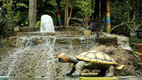 A turtle statue is in front of a waterfall Stock Photos