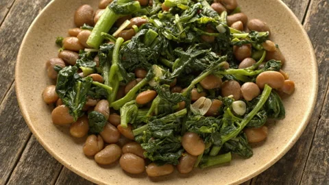Tuscan butter beans stew with rapini and garlic rotating in bowl closeup Stock Footage 342276340