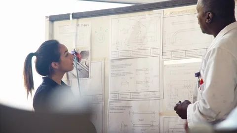Tutor Discussing Technical Drawings With Apprentice Engineer Stock Footage 86601996