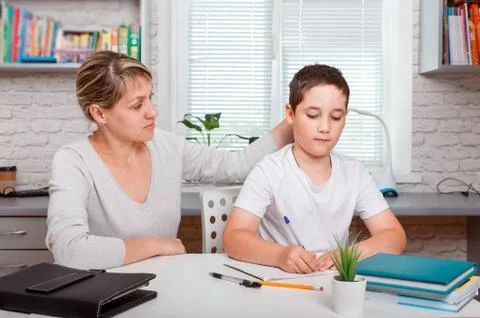 The tutor is engaged with the child, teaches to write and count Foto stock