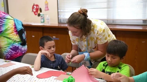 Tutor showing child how to thread needle at vacation bible school Видео 114426373