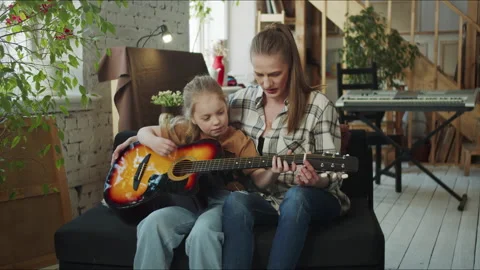The tutor teaches the child to play the guitar. The girl is uncomfortable Stock Footage 172864136