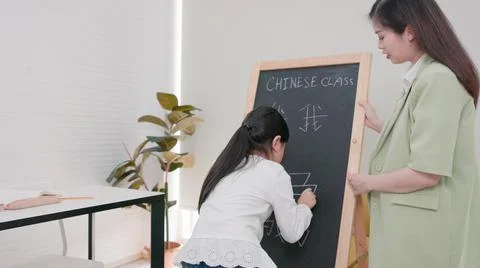 In tutorial school, Asian students learn to write in both English and Chinese Fotos Stock