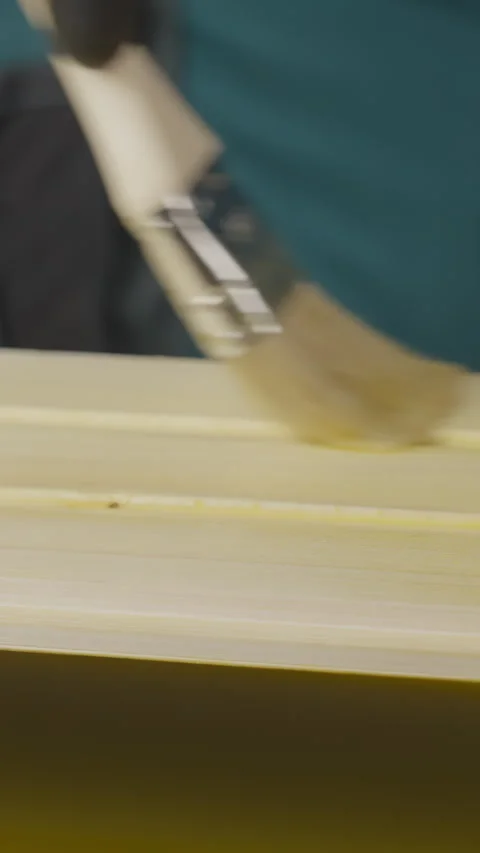 A tutorial shows treating wood with a yellow liquid, ensuring even coverage 動画素材 306051574