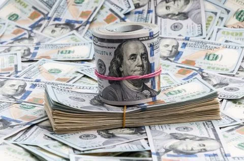 Tutu and roll of dollars on a background of bills of one hundred dollars. Stock Photos