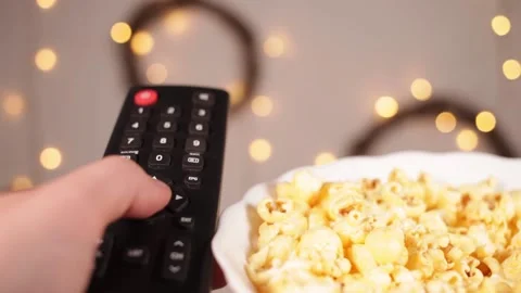 TV remote control closeup Fingers press buttons Boke and yellow Christmas lights Stock Footage 146449065