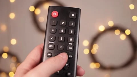 TV remote control closeup Fingers press buttons Boke and Christmas lights on a Stock-Footage 146449869