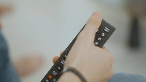 A TV remote control, a finger pressing the on / off button Stock Footage 93875718