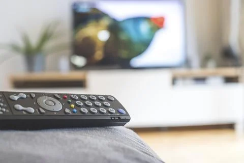 TV remote control in the foreground, tv in the blurry background. Streaming Foto stock