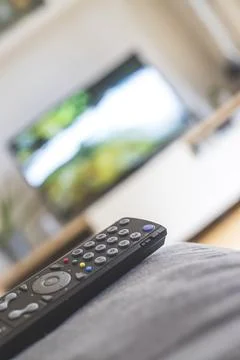 TV remote control in the foreground, tv in the blurry background. Streaming Foto stock