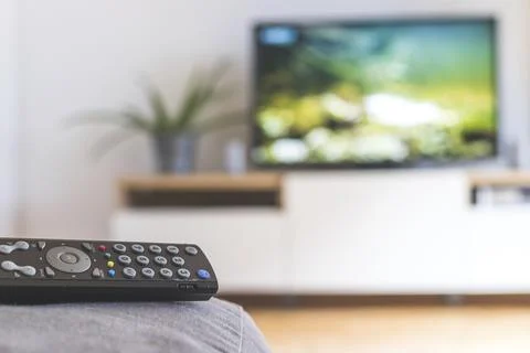 TV remote control in the foreground, tv in the blurry background. Streaming Foto stock