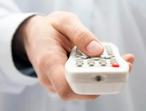Tv remote control in hand Stock Photos