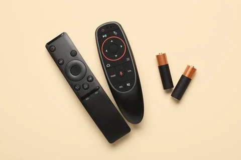 TV remote controllers with batteries on beige background 库存照片