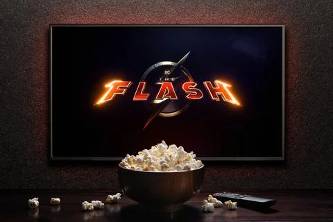 TV screen playing The Flash trailer or movie. TV with remote control and popc Stock Photos