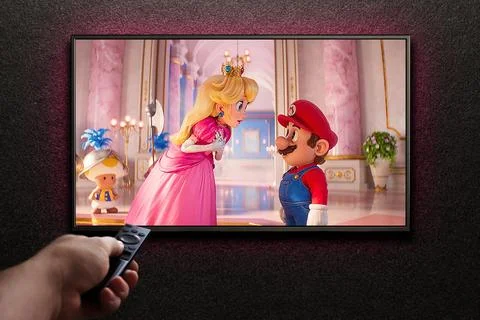 TV screen playing The Super Mario Bros. Movie trailer or movie. Man turns on  Stock Photos