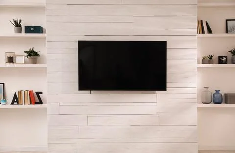 Tv set mounted on wall between niches with shelves in room. Interior design Stock Photos