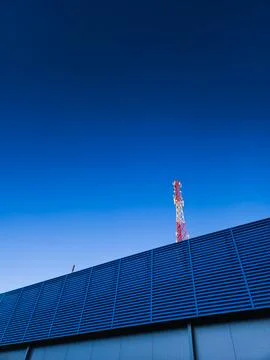 A TV tower on the background of a clear, evening, blue sky, and a building Stock Photos