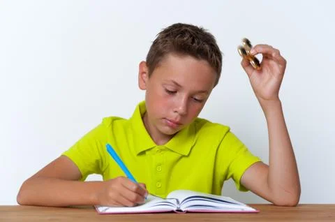 Tween boy doing homework while playing spinner Stock Photos