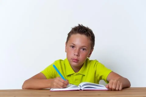 Tween boy sitting at the table with exercise book Stock Photos
