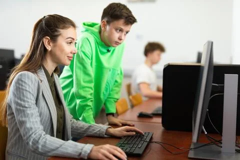 Tween schoolboy helping young puzzled woman working with computer Stock Photos
