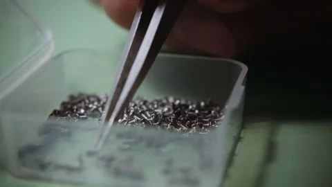 Tweezers extracting a small nut from a small box Stock Footage 75708890