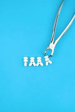 Tweezers hold tiny tooth models on blue vertical Stock Photos
