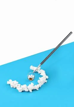 Tweezers holding tiny tooth models on two tone background Stock Photos