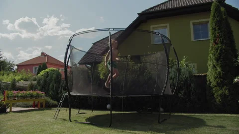 Twelve-year-old boy on backyard trampoline Stock Footage 255311284