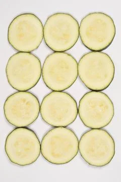Twelve Zucchini Slices in Grid Pattern on White Stock-Fotos