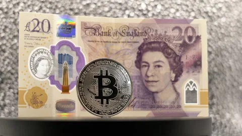 Twenty pound note and bitcoin rotating on display modern finance and traditional Stock Footage 321829708