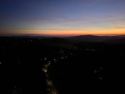 Twilight aerial perspective capturing curving street with glowing headlights Stock Photos