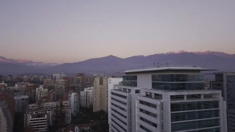 Twilight drone glide past white office tower toward Andes Santiago Chile Vídeos de archivo 334637294