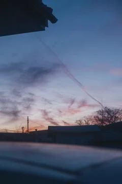 Twilight falls over rooftops beneath a swirling sky Stock Photos