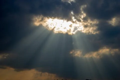 Twilight rays or stretches of the sun. Light through clouds diverge in hand. Stock Photos