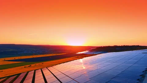 Twilight sky above solar panel arrays and golden wheat fields. Gradient pink and 動画素材 336899886