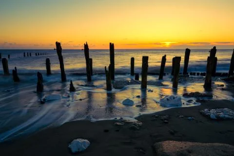 Twilight sky over soft motion sea and wooden posts. Spurn Point, East Yorkshi Stock Photos