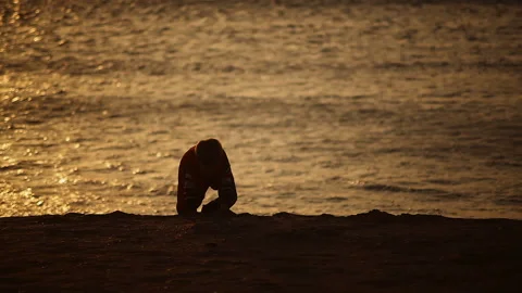 Twilight Sunset A boy plays with pebbles shells on the seashore by the water Stock-Footage 150249752