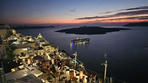 Twilight view of Santorini illuminated cliffside village, with glowing terrac Stock Photos