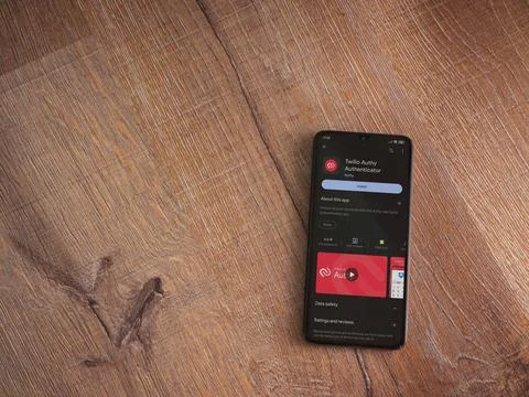 Twilio Authy Authenticator app play store page on smartphone on wooden back.. Stock Photos