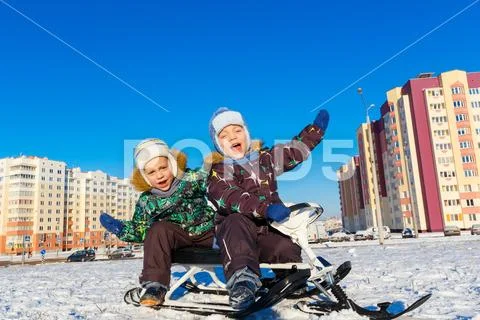 Twin brothers posing on snow scooter Stock Photos