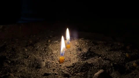 Twin Candle Flames in Darkness on Sandy Ground Видео 265398286