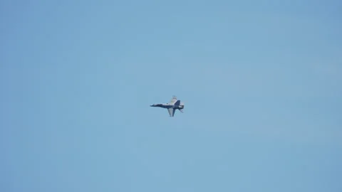 Twin engine military fighter jet banking in clear blue sky 動画素材 336455355