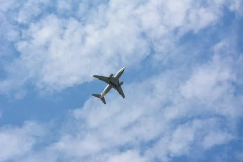 Twin engine passenger plane high in blue sky with clouds. View from below Stock Photos