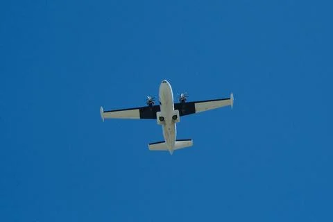 Twin-Engine Propeller Plane Flying in Clear Blue Sky Stock Photos