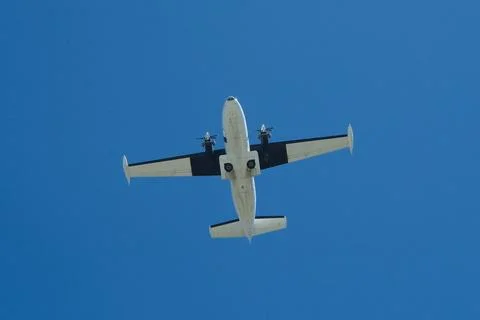 Twin-Engine Propeller Plane Flying in Clear Blue Sky Stock Photos