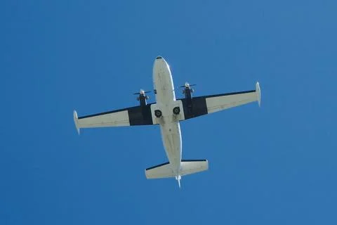 Twin-Engine Propeller Plane Flying in Clear Blue Sky Stock Photos