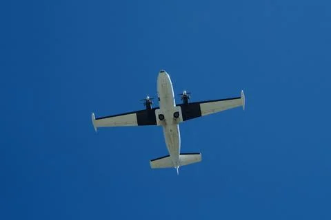 Twin-Engine Propeller Plane Flying in Clear Blue Sky Stock Photos